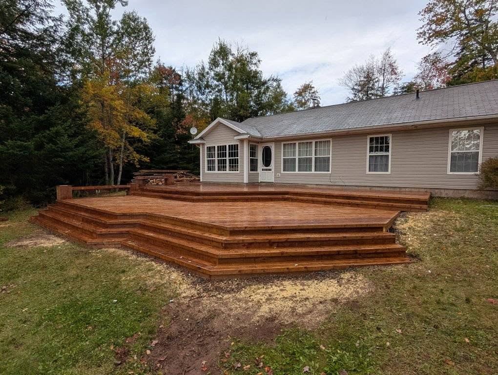 Wide multi-level cedar deck with wrapping stairs built across the back of a Nova Scotia bungalow.
