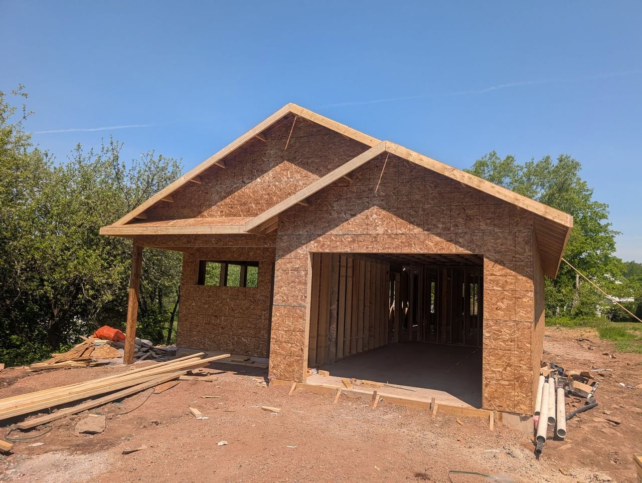 Detached two-bay garage framed and sheathed with OSB, gable roof complete, ready for roofing.
