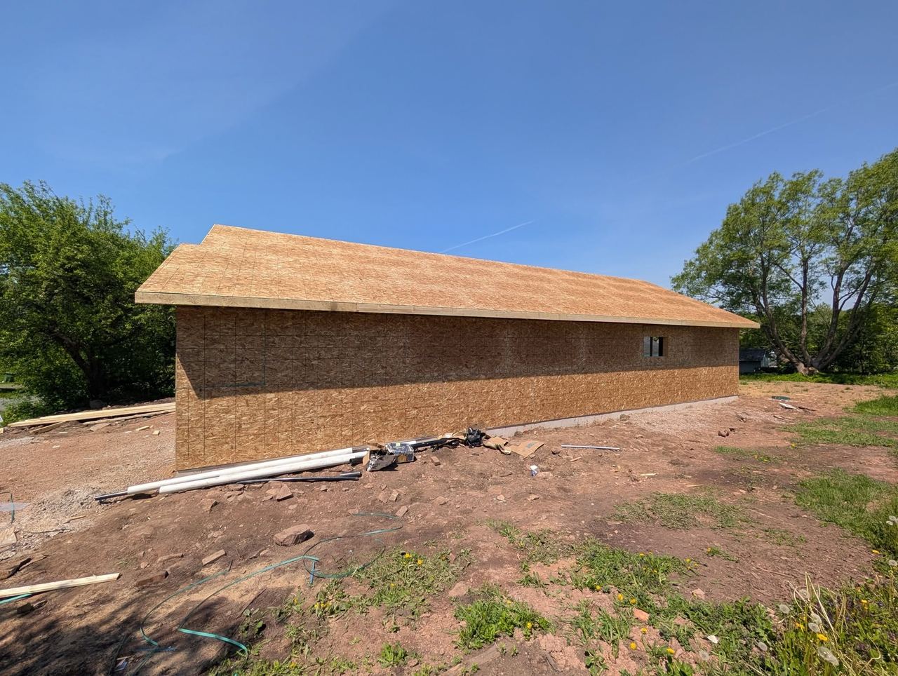 Long low garage building fully sheathed under a clear blue sky.